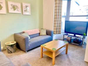 a living room with a couch and a tv at Hiraeth Môn in Menai Bridge