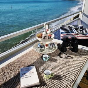 - une table avec un livre sur un balcon donnant sur l'océan dans l'établissement Studio les Trois Etoiles de Mer, à Concarneau