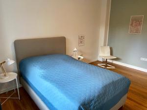 een slaapkamer met een bed met een blauw dekbed bij Zentrumsnahe schöne Altbauwohnung bis 4 Personen in Flensburg