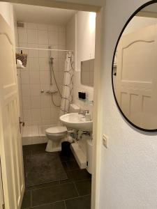 een badkamer met een wastafel, een toilet en een spiegel bij Zentrumsnahe schöne Altbauwohnung bis 4 Personen in Flensburg