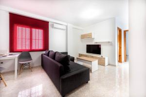 ein Wohnzimmer mit einem schwarzen Sofa und einem TV in der Unterkunft EDIFICIO CHAPARIL in Nerja