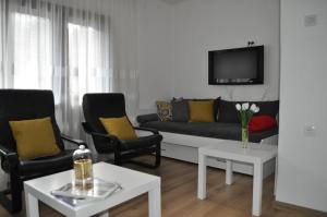 a living room with a couch and two chairs and a tv at La Pausa suite Prijepolje in Prijepolje