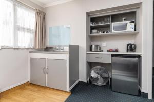 uma pequena cozinha com armários brancos e uma máquina de lavar louça em Amble Inn Motel em Masterton