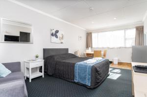 um quarto de hotel com uma cama e um sofá em Amble Inn Motel em Masterton