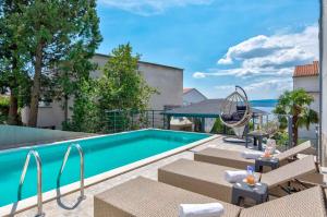 a swimming pool with patio furniture next to a house at One-Bedroom Apartment in Crikvenica LX in Dramalj