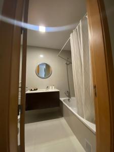 a bathroom with a tub and a sink and a mirror at Sol Poente Praia Apartment in Apúlia