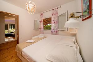 sypialnia z dużym białym łóżkiem i żyrandolem w obiekcie Apartments Milica - sea view w mieście Krilo