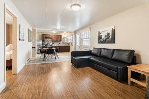 a living room with a black couch and a kitchen at Parlee Beach Motel in Shediac