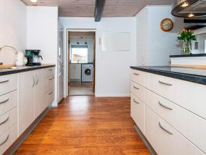 a kitchen with white cabinets and a wooden floor at 4 person holiday home in Nordborg in Nordborg