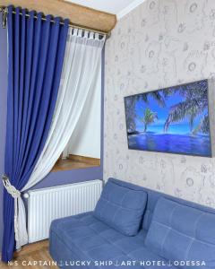 a living room with a blue couch and a curtain at Lucky Ship Art Hotel in Odesa