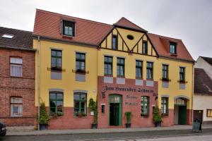 a yellow building on a street at Gasthaus und Pension "Zum Hauenden Schwein" in Wörlitz