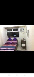 a bedroom with a bed with purple pillows and a table at Urban Deca Tower Graceysplace Unit unit 3113 Mandaluyong in Manila
