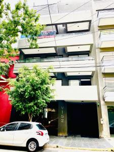 una macchina bianca parcheggiata di fronte a un edificio di APART Caballito II a Buenos Aires