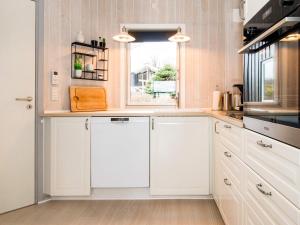 una cucina con armadietti bianchi e una finestra di Three-Bedroom Holiday home in Sjølund 1 a Hejls