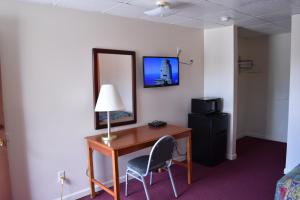 escritorio con lámpara y silla en una habitación de hotel en PLYMOUTH MOTOR LODGE, en Terryville