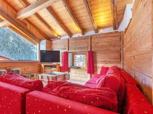 Pretty Chalet with Sauna Skiing Nearby في بيسي-نانكرويكس: غرفة معيشة بأثاث احمر وتلفزيون بشاشة مسطحة
