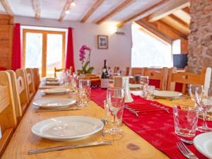 a long wooden table with plates and glasses on it at Pretty Chalet with Sauna Skiing Nearby in Peisey-Nancroix