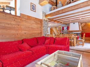 a red couch in a living room with a table at Pretty Chalet with Sauna Skiing Nearby in Peisey-Nancroix
