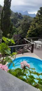a swimming pool with flowers and a view of the mountains at Gallardin Palace Hotel in Petrópolis