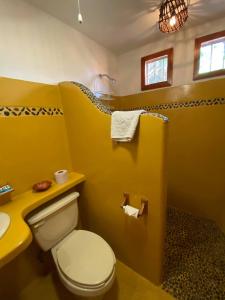 a yellow bathroom with a toilet and a sink at la vista the view in Zihuatanejo +41 photos