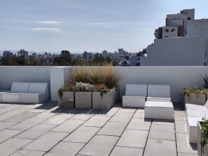 a rooftop patio with white benches and a city at Soul y Río in Córdoba