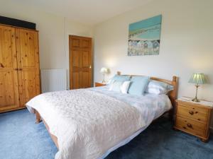 a bedroom with a large white bed and wooden cabinets at Tirionfa in Talsarnau