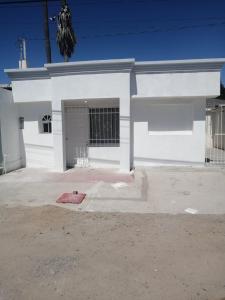 a white building with a gate and a garage at Brenda Alicia 2 in Puerto Peñasco