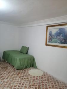 a bedroom with a green bed in a white room at Brenda Alicia 2 in Puerto Peñasco