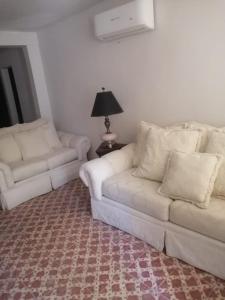 a living room with two white couches and a lamp at Brenda Alicia 2 in Puerto Peñasco
