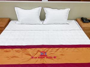 a bed with an orange and white comforter and two pillows at An Khang Hotel in Lạng Sơn