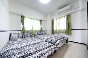 - une chambre avec 2 lits et 2 fenêtres dans l'établissement EX Itoman Apartment 503, à Teruya