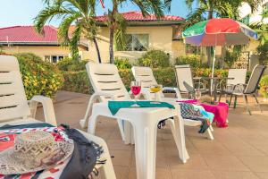 einen Tisch und Stühle mit Weingläsern und einem Regenschirm in der Unterkunft BUTTERFLY GARDEN BOUTIQUE RESIDENCES by Frasier, A Lifestyle Destination Apt and Villas 1 to 3 Bedroom units, 2 Full Bathrooms, Rain shower, Spa bath, Complete kitchen, Staff 24-7,Fast fiber optic WIFI, 55" SMART TV's, Free BBQ, in Pattaya South