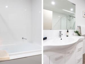 a white bathroom with a sink and a mirror at Blue Vista in Gerringong