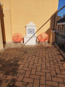 dwa pomarańczowe krzesła siedzące na patio z kominkiem w obiekcie Habitaciones Casa Sevillana Centro w Sewilli