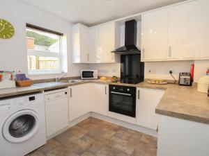 a kitchen with white cabinets and a washing machine at Rockpools in Weymouth