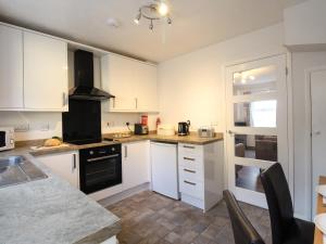 a kitchen with white cabinets and black appliances at Rockpools in Weymouth +9 photos