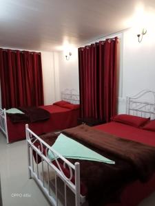a bedroom with two beds and red curtains at Rani Homestay in Cherrapunji