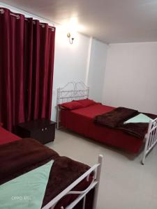 2 łóżka w pokoju z czerwonymi zasłonami w obiekcie Rani Homestay w mieście Czerapuńdżi