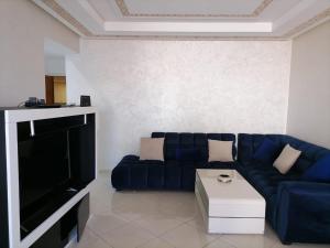 un soggiorno con divano blu e TV di Residence Ires 1 a Tangeri