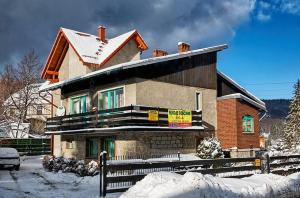 a house in the snow with a fence in front of it at Relaks in Szklarska Poręba