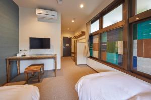 a room with two beds and a desk and a tv at HOTEL tuka miika in Ishigaki Island
