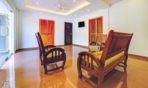 a living room with two chairs and a tv at Treebo Trend Wanderlust Residency With Mountain View in Munnar