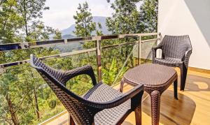 2 sedie e un tavolo sul balcone con vista di Treebo Trend Wanderlust Residency With Mountain View a Munnar