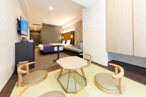 京都市にあるhotel MONday 京都丸太町のベッド、テーブル、椅子が備わるホテルルームです。