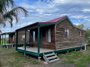 een kleine houten hut met een veranda op een veld bij Happy Wanderer Motel Cohuna 70s style in Cohuna