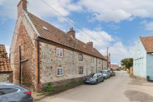 un vecchio edificio in mattoni con auto parcheggiate accanto di Driftwood Cottage pets go free WiFi included a Hunstanton