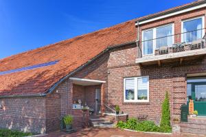 een stenen huis met een veranda en een balkon bij Ferienwohnungen auf dem Ferienhof an der Schafweide in Werdum