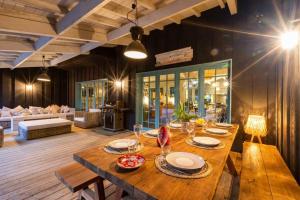 una sala da pranzo con tavolo in legno e un soggiorno di La Villa du Phare - 240 m² avec 5 chambres piscine a Lège-Cap-Ferret
