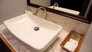 lavabo blanco en el baño con espejo en Napalai Hotel, en Udon Thani