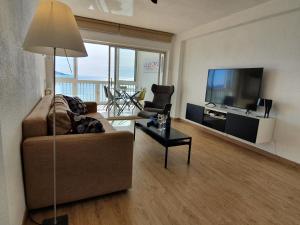un soggiorno con divano e TV a schermo piatto di Esmeralda, Benidorm Beachfront Poniente, 1st line Frontal Seaview, Ocean Terrace a Benidorm
